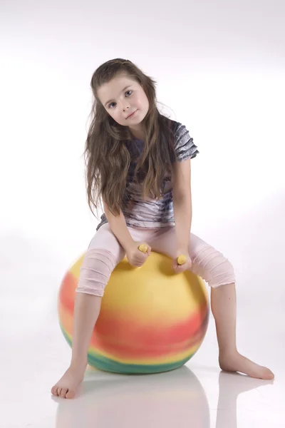 Fille sur une balle en caoutchouc coloré — Photo