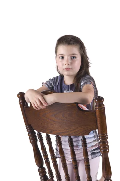 Little girl sits on a beautiful, carved, wooden chair — Stock Photo, Image