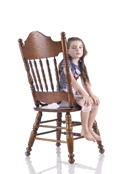Bambina siede su una bella, intagliato, sedia di legno — Foto Stock