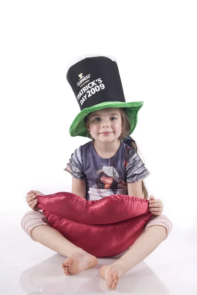 Little girl sitting on the floor in a black hat, holding a toy soft lips — Stock Photo, Image