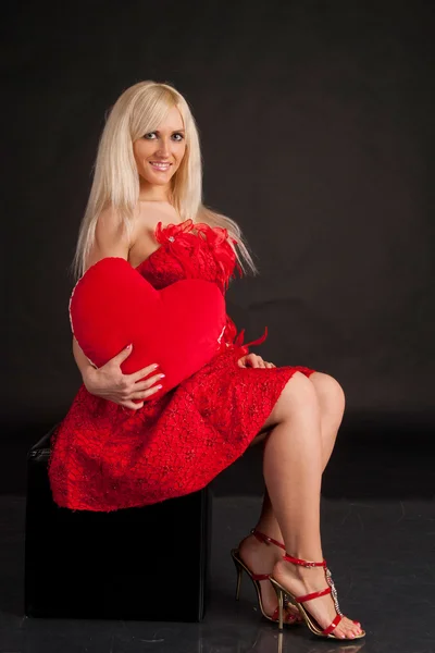 Çekici bir kadın kırmızı bir kalp ısırma — Stok fotoğraf