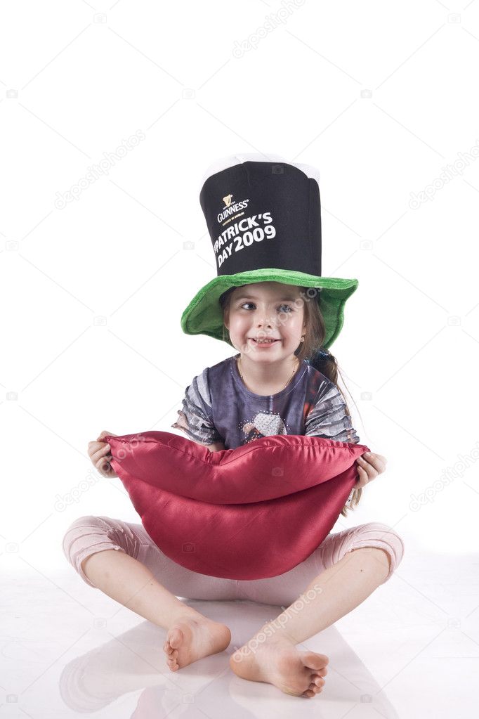 Little girl sitting on the floor in a black hat, holding a toy soft lips