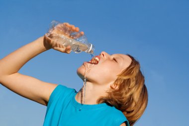 Thirsty child drinking water from bottle clipart
