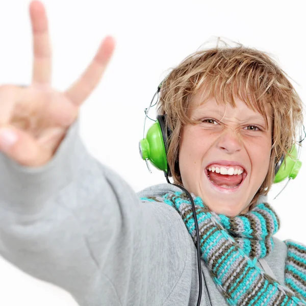 Gelukkig kind v-teken doen en luisteren naar muziek hoofdtelefoon dragen. — Stockfoto