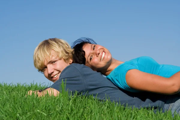Glada leende, teen par om på gräs på sommaren — Stockfoto