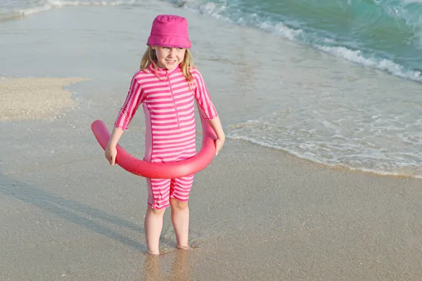 Маленький ребенок на пляже отдыха с солнцезащитным костюмом и шляпой . — стоковое фото