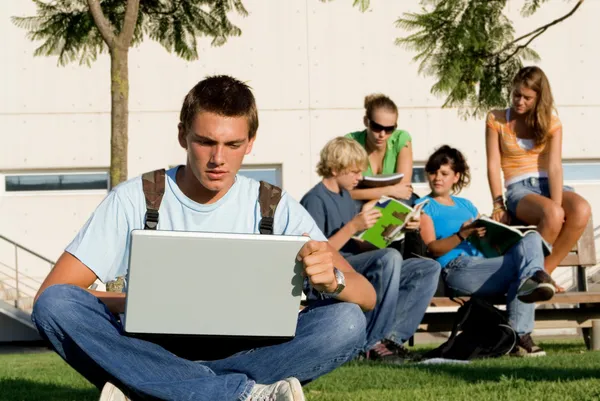 Estudiantes con ordenadores portátiles y libro en el campus —  Fotos de Stock
