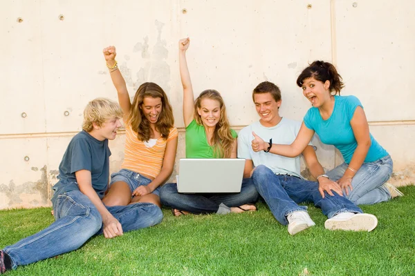 Grupo de adolescentes con manos de computadora portátil levantadas para el éxito o ganar —  Fotos de Stock