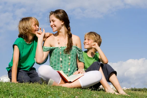 Woman reading to children outdoors — Stock Photo, Image