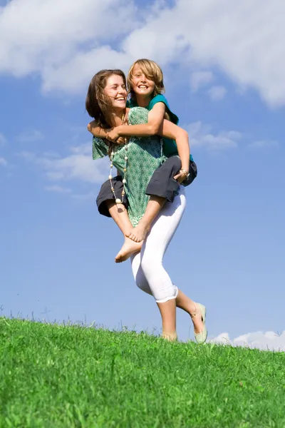 Genç çocuk ile anne ya da omzunda oynayan kız kardeşi — Stok fotoğraf