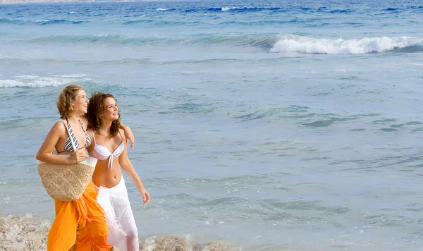 Junge Frauen spazieren in den Frühlings- oder Sommerferien am Strand entlang — Stockfoto