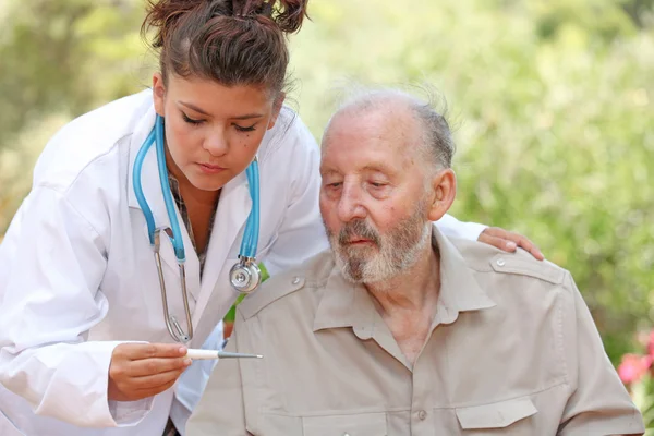 Sjuksköterska eller läkare med temperatur av äldre patient — Stockfoto