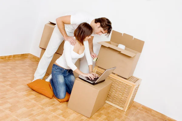 Jovem casal com laptop compra na internet na primeira nova casa — Fotografia de Stock