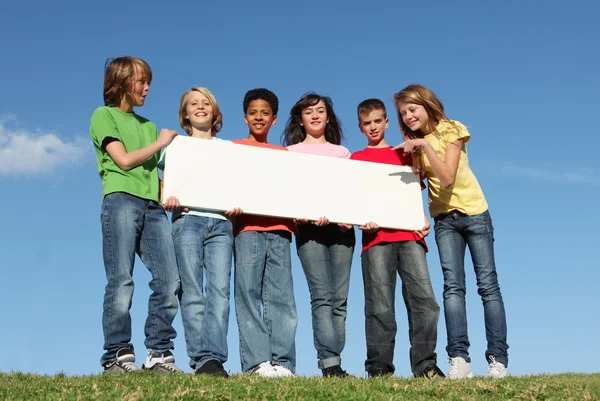 Skupina různorodých dětí drží prázdné bílé plakát — Stock fotografie