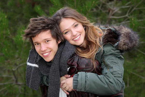 Счастливая улыбающаяся зимняя пара подростков в свиной спинке — стоковое фото