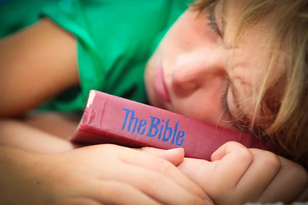 Христианский ребенок спит с хорошо изношенной и читать Библию — стоковое фото