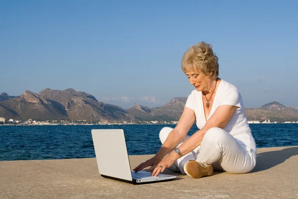 Global communication, senior woman on internet on vacation — Stock Photo, Image