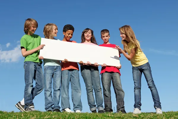 Gruppo di bambini diversi con poster bianco in bianco Immagine Stock