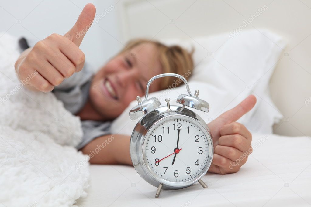 Happy child waking up with alarm clock
