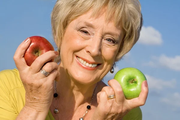 Mulher idosa saudável com maçãs para o conceito de dieta saudável — Fotografia de Stock