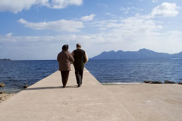 Couple sénior actif marchant au bord de la mer en vacances — Photo