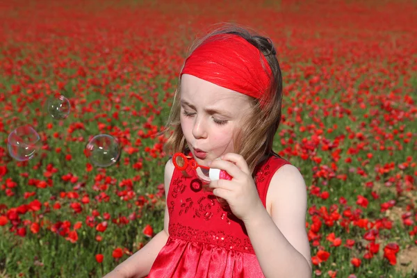 Маленька дівчинка дме бульбашки, граючи на відкритому повітрі влітку — стокове фото