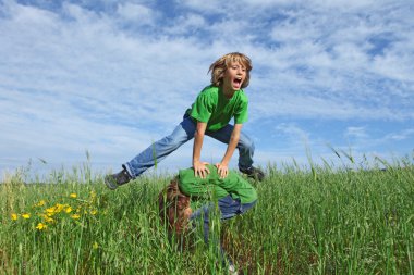 Happy healthy kids playing leapfrog outdoors in summer clipart
