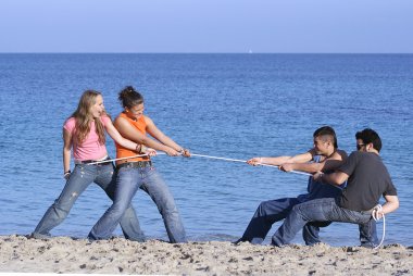 Tug of war, teens playing on beach on summer vacation or spring break clipart