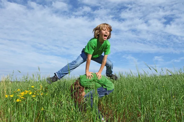 Happy healthy kids playing leapfrog outdoors in summer — Stock Photo, Image