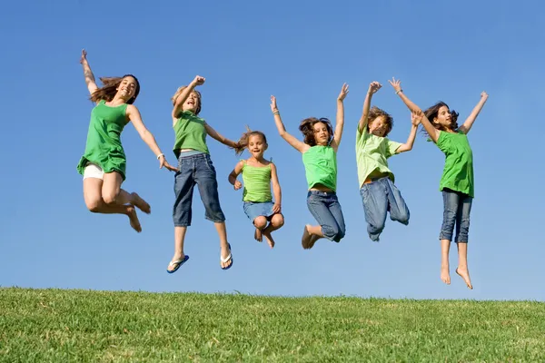 Heureux groupe d'enfants métis au camp d'été ou à l'école sautant — Photo