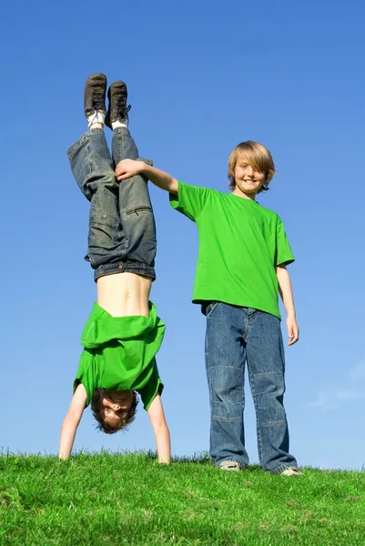 Twins, twin brothers playing outside, in summer one upside, down. Royalty Free Stock Images