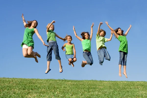Happy group of mixed race kids at summer camp or school jumping Stock Image