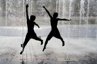 Silhouette of kids jumping in cool fountain water