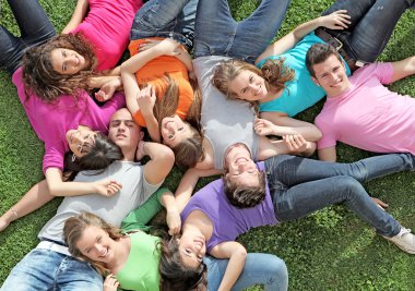 Group of happy healthy kids laying outdoors on grass at summer camp clipart