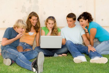 Surprised group of teenagers with laptop or notebok clipart