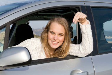 Young woman holding key to new, hire or rental car after passing, driving t clipart