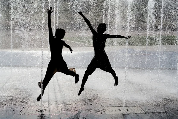 Silueta de niños saltando en agua fresca de la fuente —  Fotos de Stock