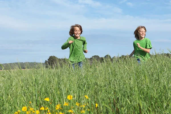 Healthy fit kids running through field — Stock Photo, Image