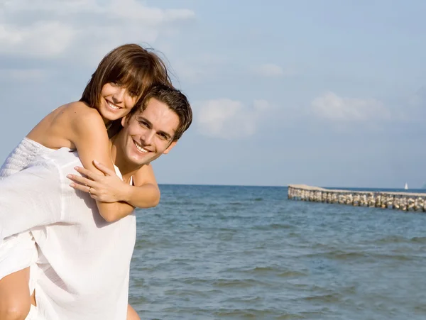 Szczęśliwa para piggyback na miodowy miesiąc wakacji lub wakacje — Zdjęcie stockowe