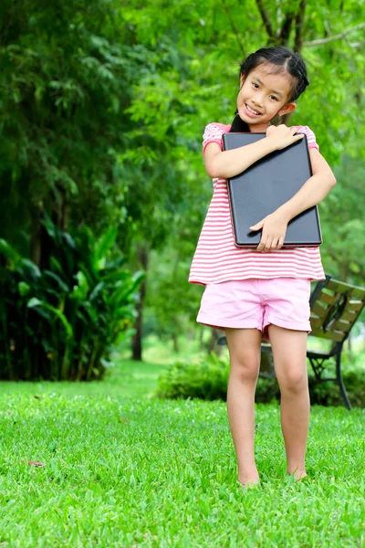 一个年轻的亚洲学校女孩用一台笔记本电脑 — 图库照片