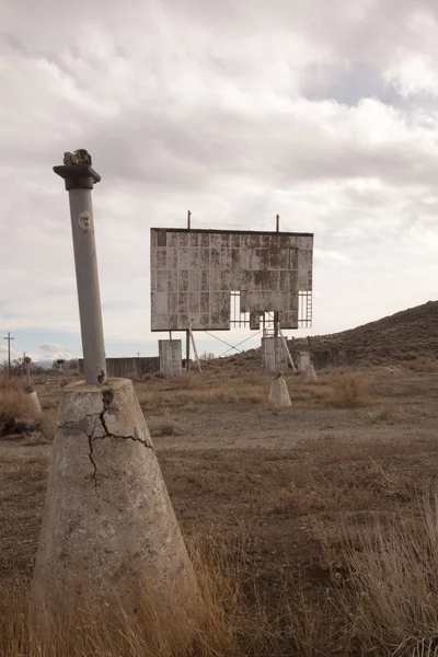 Vieux cinéma abandonné en voiture sur un désert nuageux — Photo
