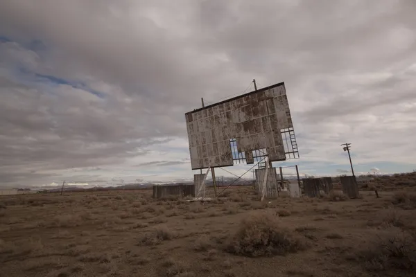 Velho cinema drive-in abandonado em um deserto dia nublado — Fotografia de Stock