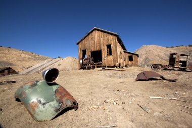 A rusty old truck fender in the forground and barn in the background. clipart