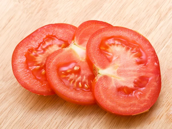 Red tomato slices on chopping board — Stock Photo, Image
