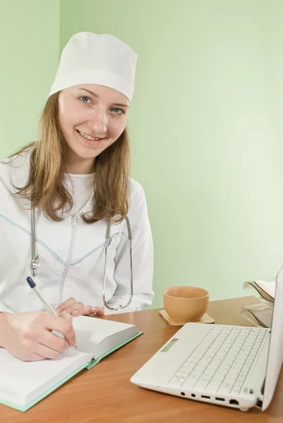 Молодая леди доктор сидит за столом — стоковое фото