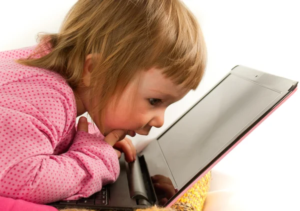Babymeisje op zoek naar de laptop het scherm op witte achtergrond — Stockfoto
