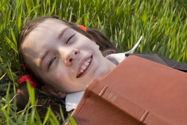 Girl with the Bible laying on the grass clipart