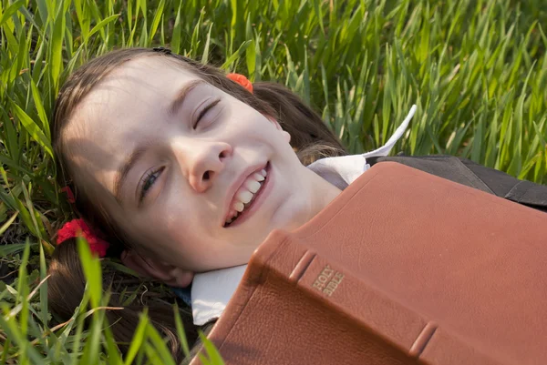 Meisje met de Bijbel opleggen op het gras — Stockfoto