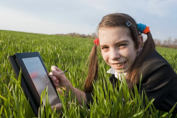 Tiener meisje met e-boek lezer opleggen van gras — Stockfoto