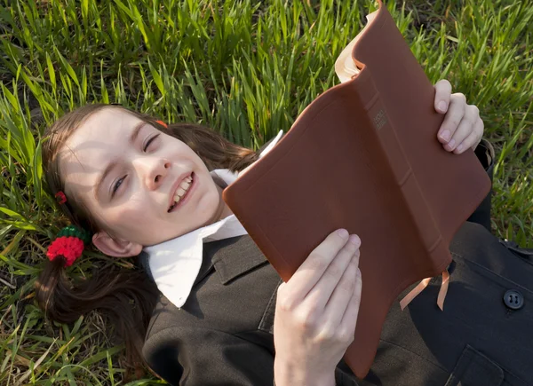 Meisje met de Bijbel opleggen op het gras — Stockfoto